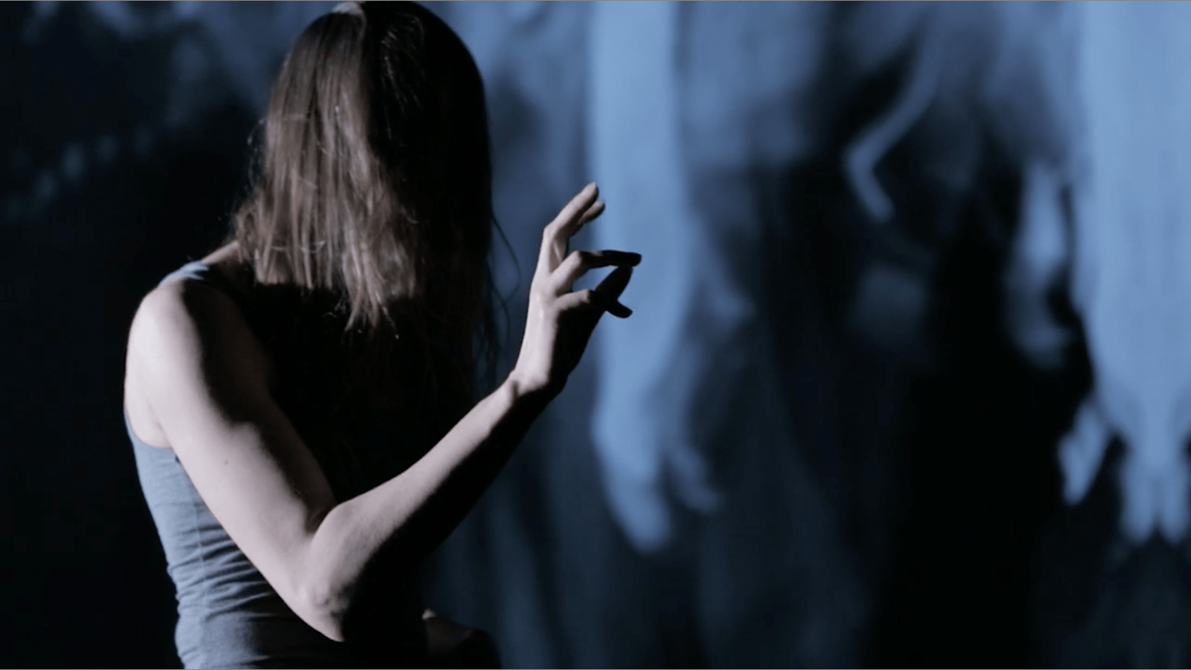 Danser med håret forans ansiktet og hånden utstrekt