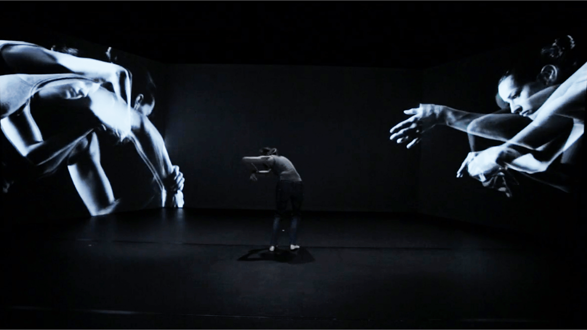 Danser med videoprojeksjon av seg selv bak