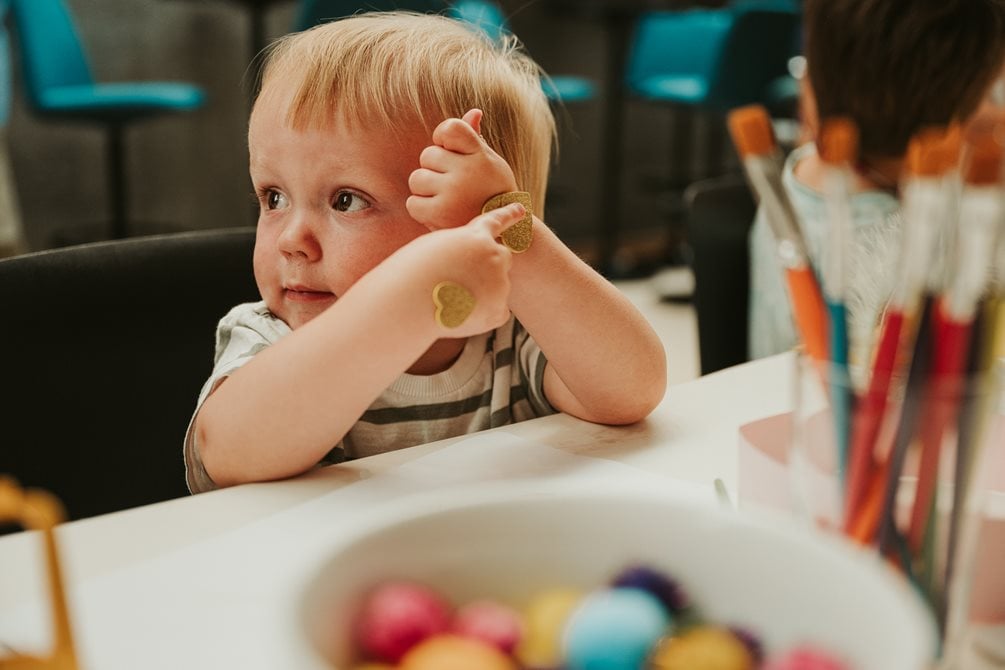 En liten gutt holder i en fargestift mens han ser til siden