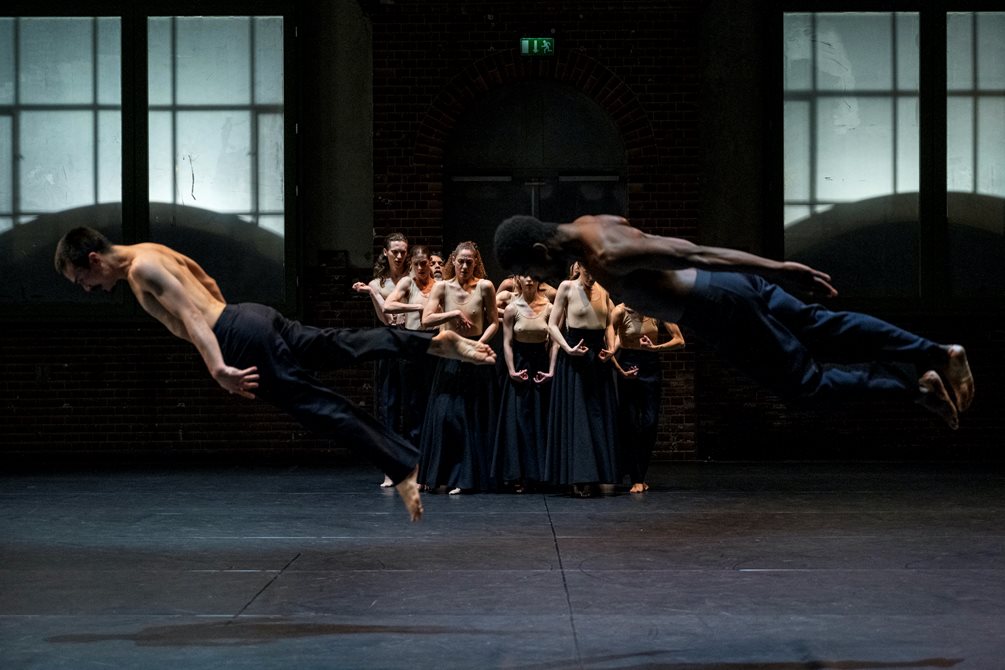 To dansere svever gjennom luften mens ensemble står bak dem